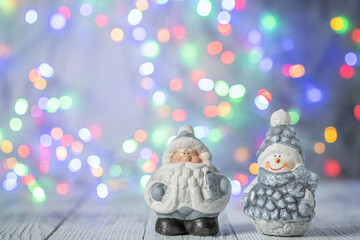 Christmas greeting card with decorative cute snowman and Santa Claus. Bokeh effect on background