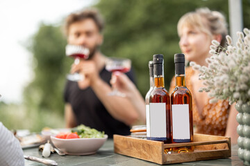 Young friends have a festive lunch outdoors, toasting and drinking wine, spending happy summer time...