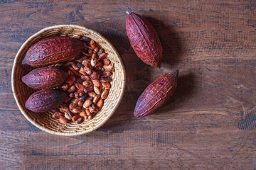 Dry cocoa pods and cocoa beans in basket on wooden background