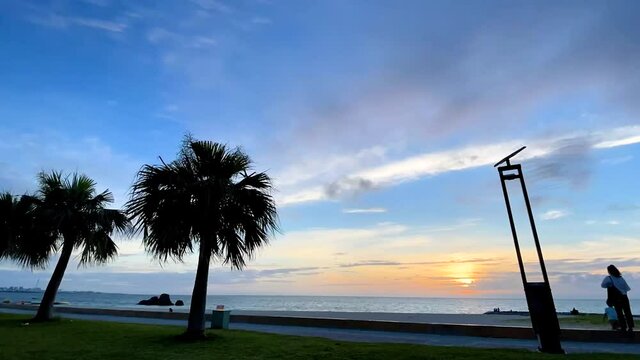 CHTAN-CHO, OKINAWA, JAPAN - JUNE 2021 : View of Araha beach (Ocean or sea) in sunset time. Wide view time lapse zoom out shot, dusk to night. Holiday, vacation and resort concept shot.