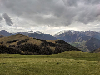 Aktoprak is a pass, known since ancient times, connecting the Baksan and Chegem gorges. Nice view of green hills covered with vegetation and high mountains with snowy peaks. Kabardino-Balkaria, Russia