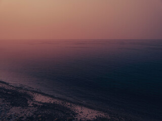 Sunrise seascape over the foggy Atlantic Ocean. Beach landscape over Falmouth Height on Cape Cod. Soft pastel image in pink and dark blue colors.