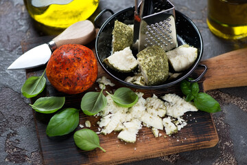 Swiss belper knolle cheese with green basil leaves and olive oil on a rustic wooden chopping board, studio shot