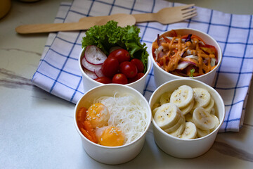 Take away healthy food in foil boxes on marble table.