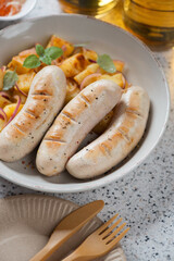 Close-up of a plate with pan fried weisswurst and potato salad, vertical shot, selective focus