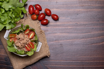 Tuna salad with fresh oak greens and tomatoes in a cup on wooden background