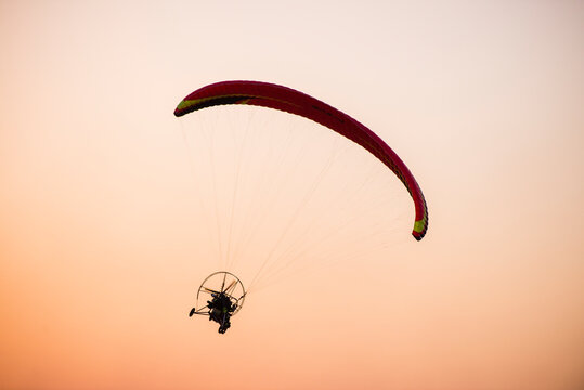 paragliding in the sky with a pilot at sunset
