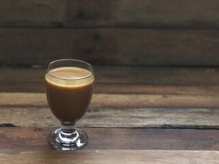 Wine glasses has iced latte coffee on empty old wood table top,dimly light,free space for text design.Concept of Relaxation in Coffee time.