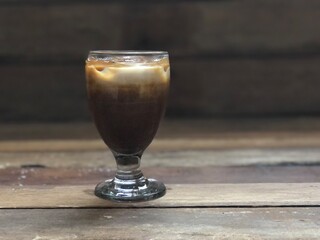Wine glasses has iced latte coffee on empty old wood table top,dimly light,free space for text design.Concept of Relaxation in Coffee time.