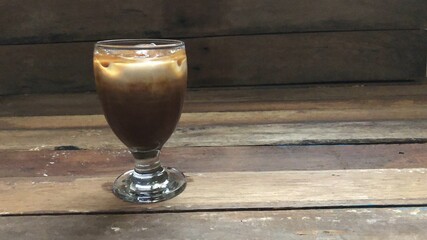 Wine glasses has iced latte coffee on empty old wood table top,dimly light,free space for text...