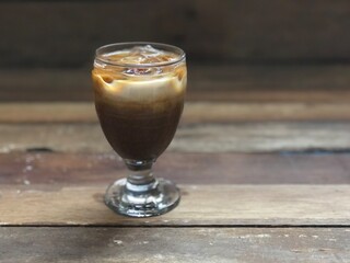 Wine glasses has iced latte coffee on empty old wood table top,dimly light,free space for text design.Concept of Relaxation in Coffee time.