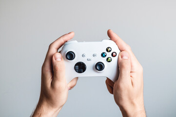 A white gamepad is in the hands of a man. © Arina Surovenko