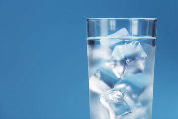 Glass with water and ice cubes on a blue background