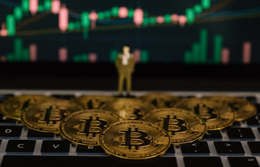 Bitcoin businessman toy and stock exchange graph background. Risk and wealth can happen in investment savings or trading in cryptocurrency innovation
