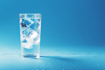 Glass with water and ice cubes on a blue background