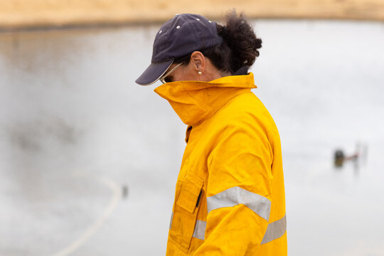 Woman firefighter with face covered by uniform looking down
