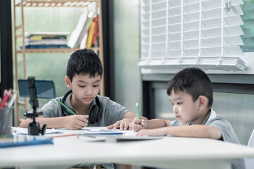 Obraz premium Child boy is using communicates on the Internet at home. homeschooling, distant learning, Asian little boy taking a class online and happy for Homeschool Quarantine