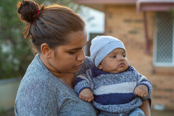 Young mother holding her baby outside