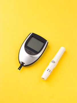 Blood glucose meter, the blood sugar value is measured on a finger on yellow background.