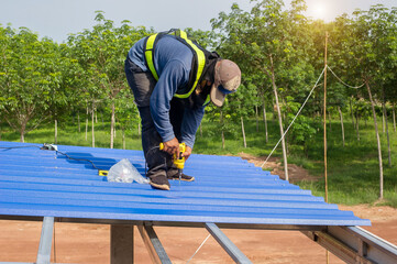 Construction worker install new roof,Roofing tools,Electric drill used on new roofs with Metal Sheet.