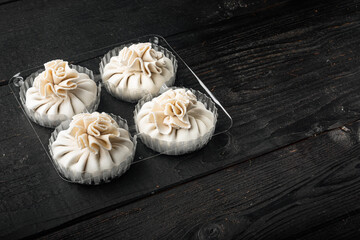 Delicious baozi, Chinese steamed meat bun, in plastic tray, on black wooden table background, with copy space for text