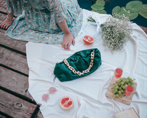 picnic by the lake, white blanket, women's purse, fruit and croissants