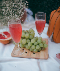 picnic by the lake, a white blanket, a woman's purse, fruit and a croissant