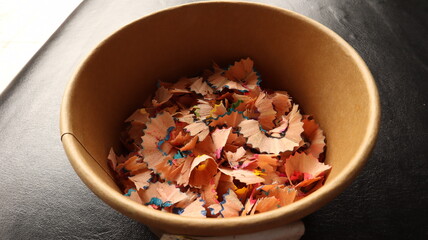 Pencil shavings Many pieces of pencil shavings lay on top of brown paper.