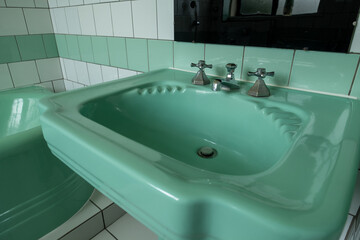 Close up of original green vintage retro 1930s deco wash basin and stainless steel taps.