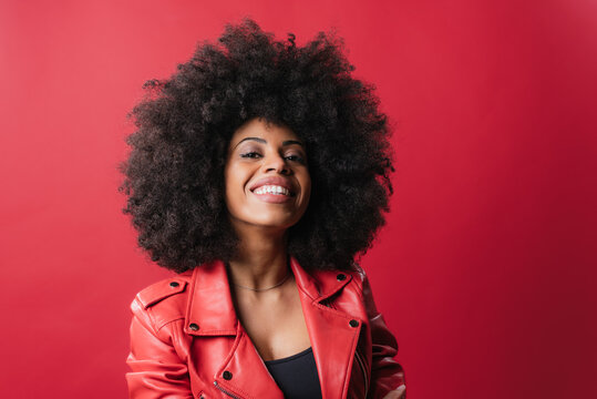 Cheerful black woman with curly hair looking at camera on red background