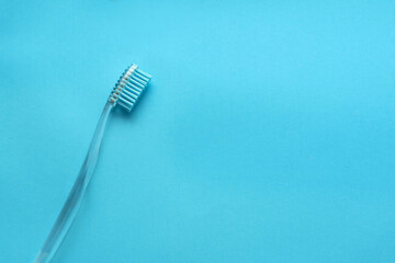 Blue transparent toothbrush on a blue background. Close up. Space fot text.