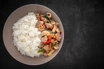 Khao Pad Ka Prao Kruang Nai Gai, Thai food, streamed rice with basil stir fried chicken offal, variety meats, pluck or organ meats on dark tone background with copy space for text, top view