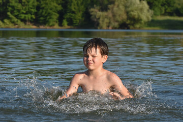 Child playing and swimming in the water. Boy splashing in a water on hot sunny day