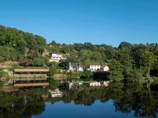 Fototapeta na wymiar French houses and old communal wash house reflecting in the River Vienne in L'Isle Jordain France