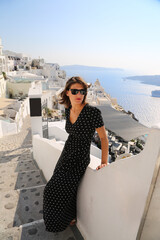 Fototapeta na wymiar Beaitufil young woman girl traveller in long dress smiling enjoying luxury life in Santorini Greece.