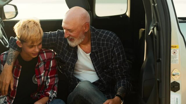 An attractive son and his father are talking while travelling on the pickup car on nature