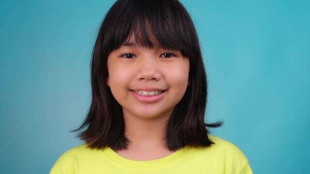 Close up portrait young Asian girl smile, Thai woman kid isolated on blue background 
