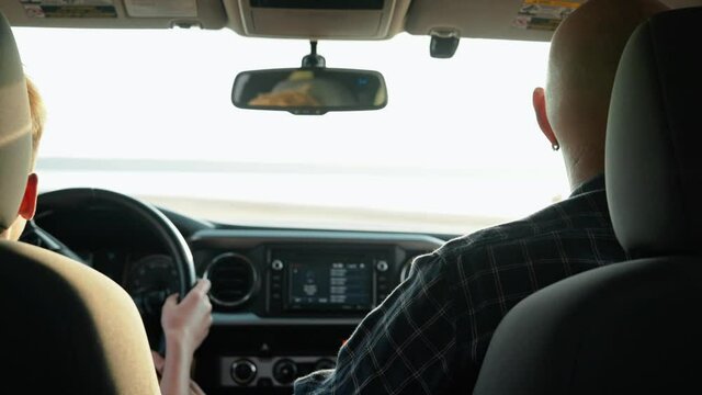 A back view of a father lets his little to drive pickup car on nature