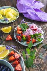 Different ice cream sorbet. Lemon and lavender, strawberry, red currant and blueberry ice cream in plates on dark wooden table surface