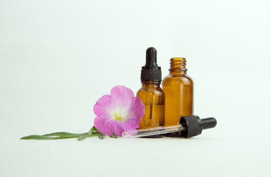 A glass bottle of essential oil with fresh flowers isolated on a white background. The concept of the basis of herbal medicine with calendula oil for aromatherapy with space for copying