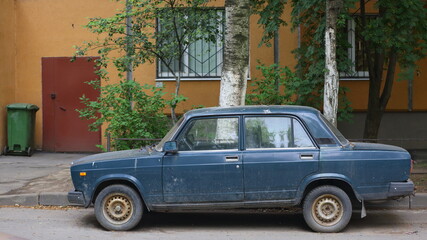 An old blue Soviet car in the courtyard of a residential building, Dybenko Street, St. Petersburg, Russia, July 2021