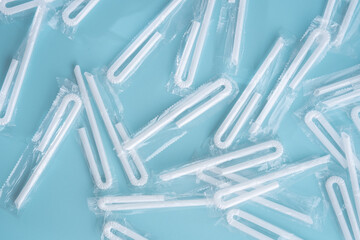 White plastic straws still wrapped on a blue background