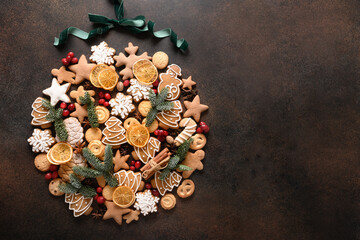Fototapeta na wymiar Creative Christmas ball of assorted cookies, cinnamon, anise stars, berries, orange chips, spruce branches on brown background. New Year greeting card. Top view. Xmas holiday background. Copy space.