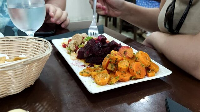Young Caucasian woman eating Moroccan mixed salad with carrots, beetroot and fish roe.