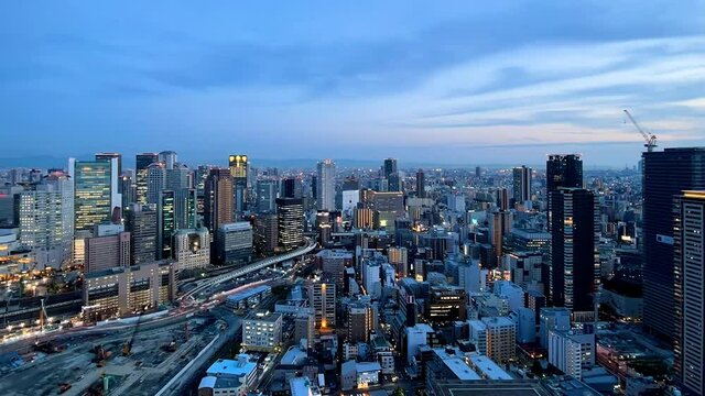 UMEDA, OSAKA, JAPAN : Aerial high angle sunrise view of CITYSCAPE of OSAKA. View of buildings and street around Osaka and Umeda station. Wide view time lapse tracking shot, night to morning.