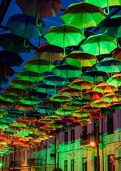 Obraz premium Colorful umbrellas in the evening. Colorful umbrellas in the sky. Street decoration from umbrellas. Background of umbrellas. 