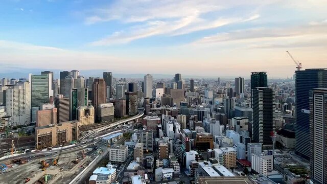 UMEDA, OSAKA, JAPAN : Aerial high angle sunrise view of CITYSCAPE of OSAKA. View of buildings and street around Osaka and Umeda station. Wide view time lapse tracking shot, night to morning.