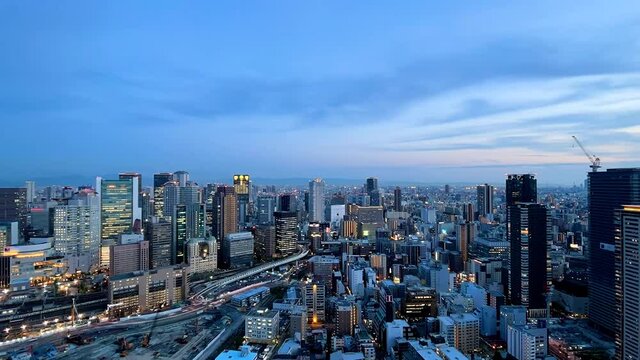 UMEDA, OSAKA, JAPAN : Aerial high angle sunrise view of CITYSCAPE of OSAKA. View of buildings and street around Osaka and Umeda station. Wide view time lapse zoom out shot, night to morning.