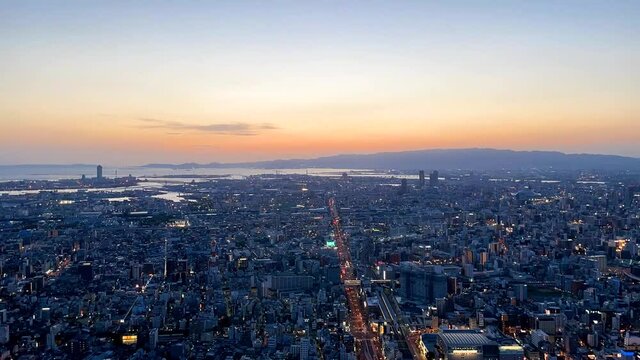 UMEDA, OSAKA, JAPAN : Aerial high angle sunset view of CITYSCAPE of OSAKA. View of buildings and street around Osaka and Umeda station. Wide view time lapse shot, dusk to night.