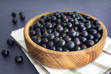 Fresh black currant in wooden bowl on dark table